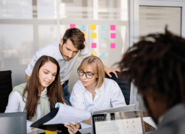 Image Of Employees Gathering And Reviewing Their Work